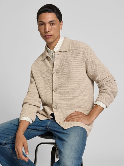 Mannenmodel draagt Cardigan aus Baumwoll-Mix van closed in beige met structuurpatroon, losse pasvorm, platte kraag, doorlopende knoopsluiting. Ganzkörperansicht van voren. Context: heren cardigan van closed, katoenmix, losse pasvorm, doorlopende knoopsluiting, structuurpatroon, platte kraag, ruglengte maat M 70 cm, schouderbreedte maat M 47 cm, mouwlengte maat M 67 cm.
