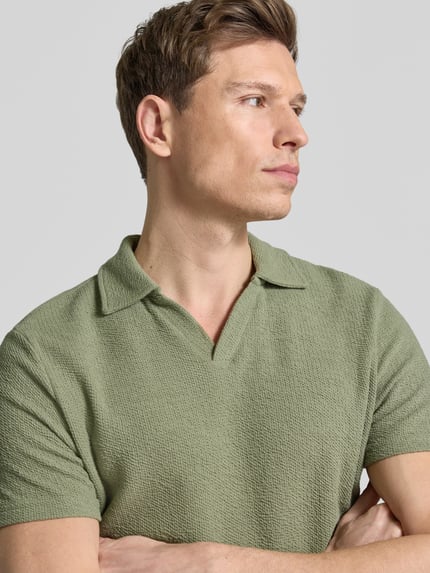 Männermodel trägt Regular Fit Poloshirt aus Baumwoll-Mix von MCNEAL in Waffle-Piqueé, kurzärmelig, Umlegekragen, Nahaufnahme Oberkörper.