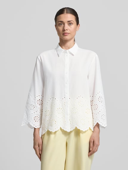 Kobiece modelka nosi Regular Fit Bluse mit Lochstickerei od Betty Barclay, biała bawełna z haftem ażurowym, kołnierzyk koszulowy, zapięcie na guziki, długość tyłu 63 cm, długość rękawa 50 cm, widok całej sylwetki z przodu.