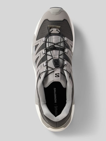 Produktfoto, Sneaker mit profilierter Sohle Modell 'XC ROAM' von Salomon in Grau und Schwarz, abgerundete Spitze, Schnürung, Logo auf der Zunge, strukturierte Textur, Herren Sneaker, Größe 44 mit 4 cm Absatzhöhe, 8 cm Schafthöhe und 8 cm Schaftweite.