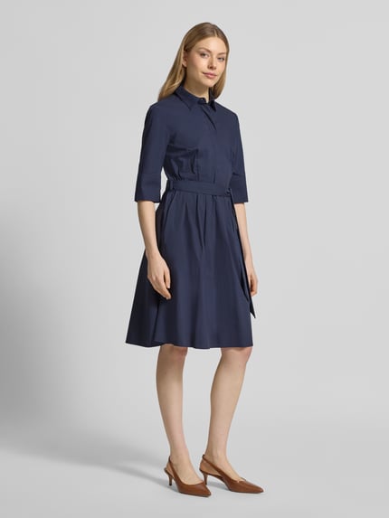 Modelka nosi Knielanges Hemdblusenkleid mit Bindegürtel von Christian Berg Woman Selection, granatowy, bawełniany materiał z domieszką stretchu, A-linia, ukryta listwa guzikowa, pasek, długość do kolan, długość pleców w rozmiarze 36: 99 cm, szerokość w rozmiarze 36: 48 cm, długość rękawa w rozmiarze 36: 37 cm, pełna sylwetka z przodu.