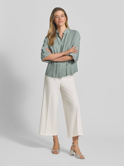 Frauenmodel trägt Wide Fit Stoffhose mit Bügelfalten Modell 'Juli' von Betty Barclay aus Elastischer-Material-Mix, Farbe Weiß, Ganzkörperansicht von vorne.