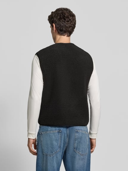 Männermodel trägt Weste mit Fleece-Struktur von Lacoste in Schwarz, strukturierte Oberfläche, Reißverschlusstaschen, Ganzkörperansicht Rückansicht.