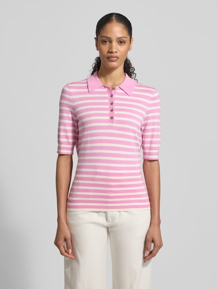 Frauenmodel trägt Poloshirt aus Viskose-Mix von Christian Berg Woman mit rosa-weißen Streifen, gerader Schnitt, Polokragen, 1/2-Arm, Ganzkörperansicht von vorne.