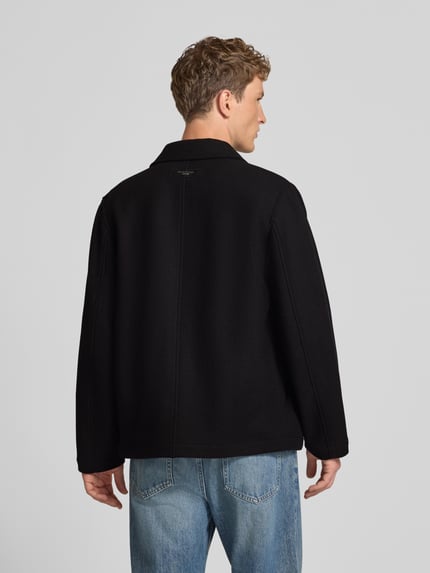 Männermodel trägt Regular Fit Blouson aus Woll-Mix von Marc O'Polo DENIM in Schwarz, lockere Passform, glatte Textur, Ganzkörperansicht Rückansicht.
