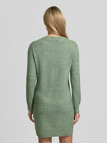 Frauenmodel trägt tailliertes Strickkleid mit Rundhalsausschnitt Modell 'DOFFY' von VERO MODA in hellgrüner Melange-Strickoptik, Mini-Länge, Regular Fit, Ganzkörperansicht Rückansicht.