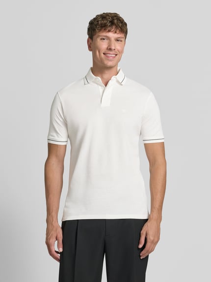 Männermodel trägt Slim Fit Poloshirt mit Label-Stitching von Emporio Armani, Reine Baumwolle, verdeckte Knopfleiste, Ganzkörperansicht von vorne. Rückenlänge bei Größe M: 68 cm.
