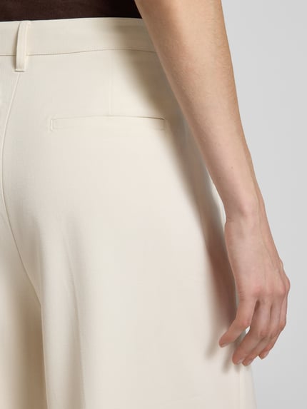 Vrouwenmodel draagt Culotte met Franse steekzakken model 'TAILOR' van Copenhagen Muse, materiaalmix met viscose, wide leg fit, haakjes- en ritssluiting, biezen, strookzak aan de achterkant, lichte crème kleur, gladde structuur, detailopname achterkant.