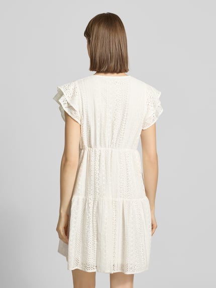 Vrouwenmodel draagt tailliertes blousejurk uit katoenmix model 'HELENA' van Only in effen kleuren met borduursel, minilengte, zonder kraag, V-hals, korte knoopsluiting, korte mouw, onderjurk, rugaanzicht, detailrijke textuur