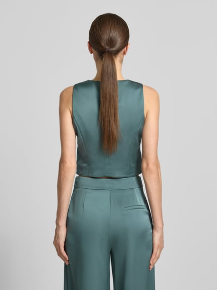 Frauenmodel trägt Weste aus Satin mit V-Ausschnitt von Jake*s Cocktail in Grün, Slim Fit, glatte Oberfläche, Rückenansicht, Ganzkörperansicht Rückansicht.