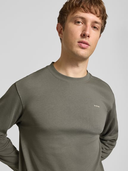 Männermodel trägt Langarmshirt mit kleinem Logo-Schriftzug von G-Star RAW, unifarbenes Jersey mit Struktur, Nahaufnahme Oberkörper.