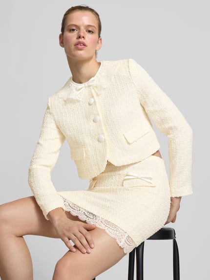 Frauenmodel trägt Damen Jacke mit Woll-Anteil von Self-Portrait in Creme mit Spitze, Pattentaschen, Knopfleiste, Material-Mix, Nahaufnahme Oberkörper.