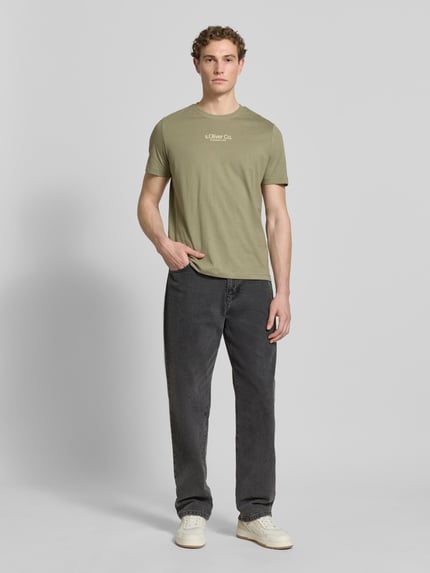 Männermodel trägt Regular Fit T-Shirt aus reiner Baumwolle von s.Oliver RED LABEL in Optik: Unifarben mit Label-Print, Rundhals, Kurzarm, Ganzkörperansicht von vorne.