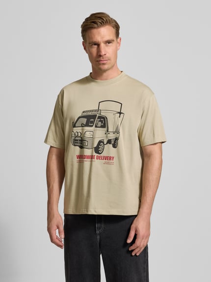 Männermodel trägt T-Shirt mit Motiv-Print Modell 'Baine' von WOODBIRD in Beige, aus Bio-Baumwolle, Regular Fit, Nahaufnahme Oberkörper.
