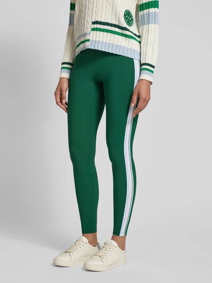 Vrouwenmodel draagt Slim Fit Leggins met elastische band van Marc Cain in groen met witte siergarnering, elastische materiaalmix, slim fit, elastische band, bandwijdte maat 36 34 cm, binnenbeenlengte maat 36 76 cm, close-up onderlichaam vooraanzicht