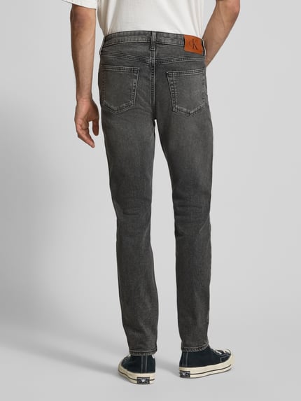 Męski model nosi Slim Fit Jeans mit Label-Patch Modell 'HEARST' od Calvin Klein Jeans, bawełna z elastanem, used-look, tylna pełna sylwetka.