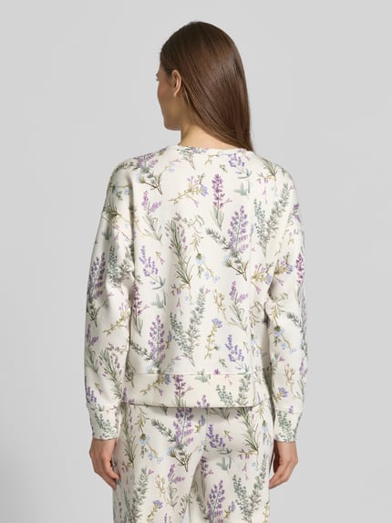 Kobiece modelka nosi Bluza Sweatshirt O-Neck mit Lavendelprint von Christian Berg Woman, mieszanka wiskozy i elastanu, luźny krój, dekolt okrągły, elastyczne wykończenia, lawendowy nadruk, widok całej sylwetki od tyłu.