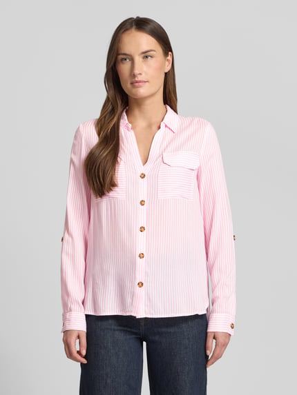 Modelka kobieca nosi różowo-białą, pasiastą Relaxed Fit Hemdbluse aus reiner Viskose Modell 'BUMPY' od Vero Moda, widok całej sylwetki z przodu.