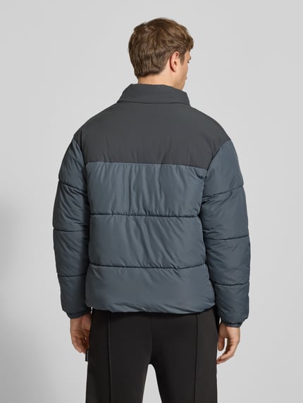 Männermodel trägt Steppjacke mit Stehkragen Modell 'RAZE' von JACK & JONES in Dunkelblau mit grauen Akzenten, Rückenansicht, Regular Fit, Eingrifftaschen, Reißverschluss, strukturierte Oberfläche, Ganzkörperansicht Rückansicht.