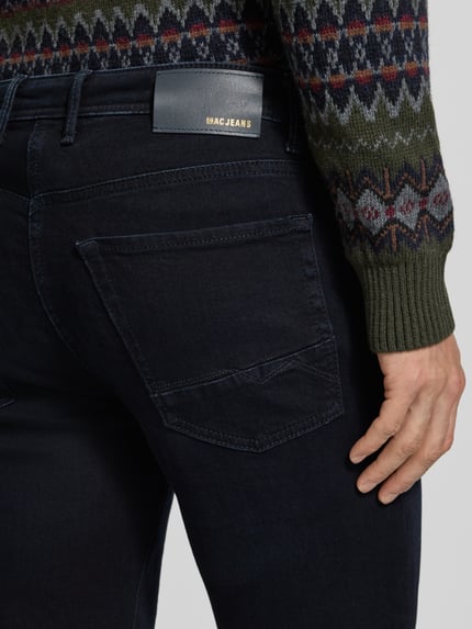 Männermodel trägt Slim Fit Jeans mit Dark-Wash-Optik Modell 'Arne' von MAC, Denim, 5-Pocket, Nahaufnahme Rückansicht.