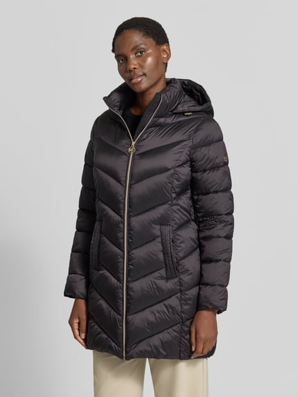 Vrouwenmodel draagt zwarte gewatteerde mantel met capuchon en ritssluiting, Steppmantel mit Kapuze und Reißverschlusstaschen von MICHAEL Michael Kors, recht model, zij-ritszakken, opstaande kraag, ruglengte maat S 86 cm, schouderbreedte 43 cm, borstwijdte 50 cm, mouwlengte 62 cm, Ganzkörperansicht van voren.
