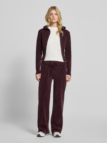 Frauenmodel trägt Sweatjacke mit Kapuze Modell 'MAYA KNIT HOODIE' von Juicy Couture, unifarben, Strickoptik, Ganzkörperansicht von vorne.