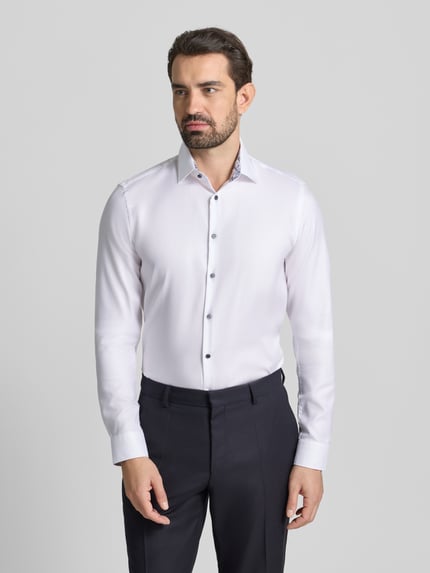 Männermodel trägt Slim Fit Businesshemd mit extra langem Arm von Jake*s, weiße Baumwolle, Kentkragen, Knopfleiste, Ganzkörperansicht von vorne