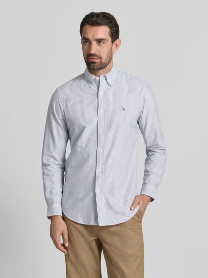 Männermodel trägt Freizeithemd mit Knopfleiste von Polo Ralph Lauren aus reiner Baumwolle, feine Streifen, Regular Fit, Ganzkörperansicht von vorne.