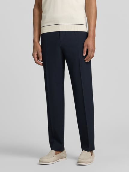 Mannenmodel draagt stoffen broek met persplooien Modell 'River' van JOOP! collectie, materiaalmix met viscose, straight fit, elastische band met knoop- en ritssluiting, steekzakken, strookzak aan de achterkant, bandwijdte maat 50: 44 cm, binnenbeenlengte: 77 cm, donkerblauw, glad oppervlak, detailopname onderlichaam, voorkant.