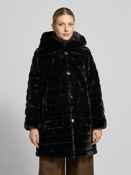 Frauenmodel trägt Regular Fit Mantel mit Wendefunktion und Webpelz-Innenseite von PETITE M. in Schwarz, glatte Knopfleiste, seitliche Eingrifftaschen, weiche strukturierte Oberfläche, Ganzkörperansicht von vorne, Rückenlänge 85 cm, Schulterbreite 39 cm, Brustweite 50 cm, Ärmellänge 62 cm.
