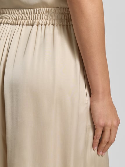 Frauenmodel trägt Regular Fit Wide Leg Hose aus reiner Viskose Modell 'TALIA' von BOSS Orange in Optik: Unifarben, Satin, Materialverarbeitung reine Viskose, Detailaufnahme seitlicher Eingrifftasche.