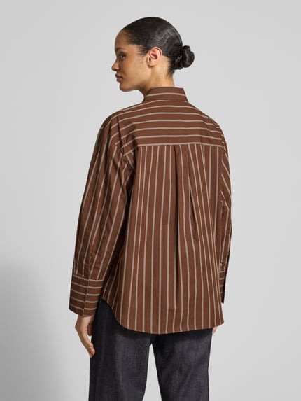 Frauenmodel trägt Relaxed Fit Hemdbluse mit Brusttasche Modell 'LLAMA' von Mango, braun mit weißen Streifen, reine Baumwolle, Ganzkörperansicht Rückansicht.