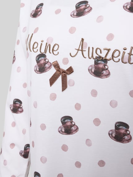 Vrouwenmodel draagt Nachthemd uit zuivere katoen Modell 'Meine Auszeit' van LOUIS & LOUISA met stippen, strikapplicatie en statement-stiksel, detailopname.