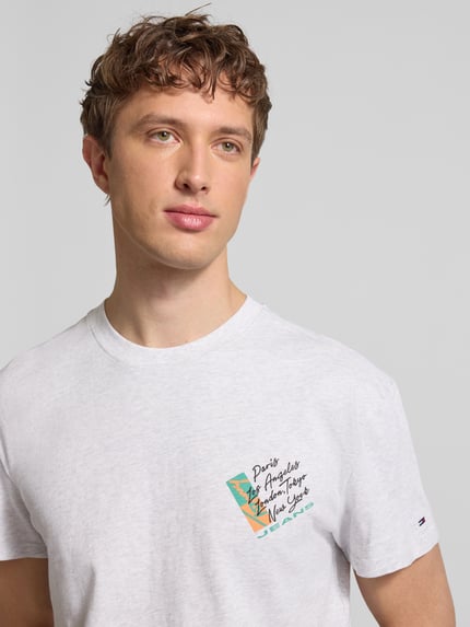 Männermodel trägt Regular Fit T-Shirt aus reiner Baumwolle von Tommy Jeans, unifarben mit Label Print, Nahaufnahme Oberkörper