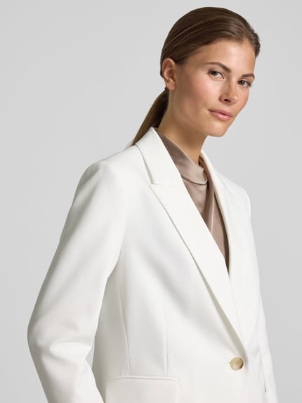 Frauenmodel trägt Shaped Fit Longblazer mit steigendem Reverskragen von s.Oliver BLACK LABEL, Optik: Unifarben, Passform: Shaped Fit, Kragenform: Reverskragen, Rückenschlitz, einreihige Knopfleiste, Ärmelform: Langarm, Pattentaschen, glatte Oberfläche, weiche Farbgebung, Nahaufnahme Oberkörper.