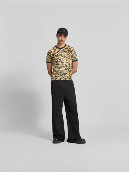 Męski model nosi T-Shirt mit Allover-Animal-Print od Kenzo z bawełny, krój slim fit, okrągły dekolt, krótki rękaw, długość tyłu 61 cm w rozmiarze M, widok całej sylwetki z przodu.