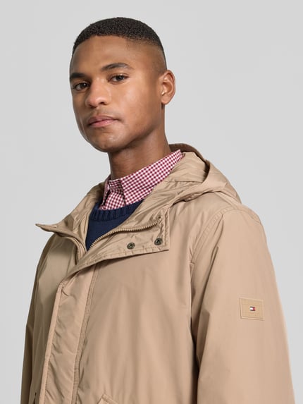 Männermodel trägt Regular Fit Funktionsjacke mit Kapuze von Tommy Hilfiger, Optik: Unifarben, Label-Applikation, Logo-Patch, Nahaufnahme Oberkörper.
