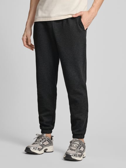 Männermodel trägt Sweatpants mit Logo und elastischem Bund von GAP in Dunkelgrau, Baumwoll-Mix, Regular-Fit, Nahaufnahme Unterkörper.