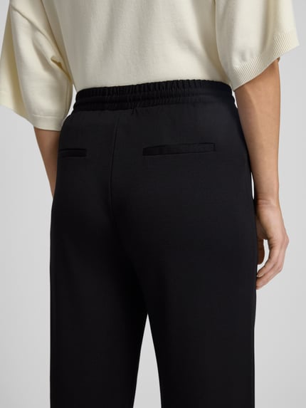 Kobiece model prezentuje Stoffhose mit elastischem Bund Modell 'NANNI' od FREE/QUENT, czarne, gładka faktura, widok z tyłu, zbliżenie na talię.