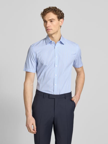 Männermodel trägt Slim Fit Business-Hemd aus Baumwolle mit Kentkragen von Jake*s, hellblau mit weißen Streifen, Halbarm, Ganzkörperansicht von vorne.