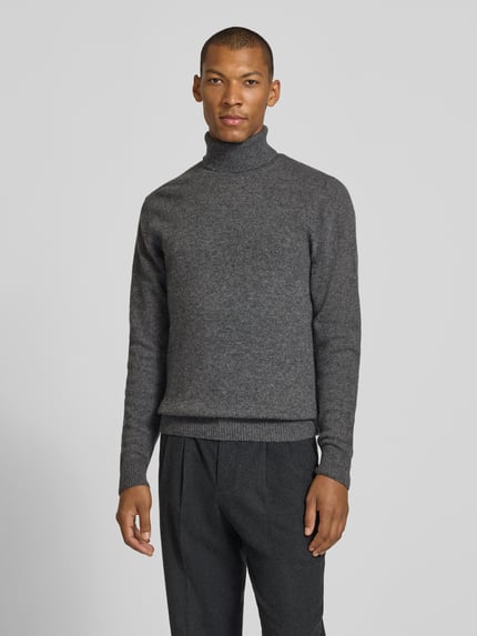 Männermodel trägt Slim Fit Rollkragenpullover aus Woll-Mix Modell 'Karl' von Casual Friday in Grau mit gerippten Abschlüssen, Ganzkörperansicht von vorne.