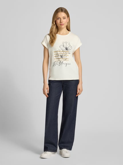 Vrouwenmodel draagt T-shirt met fixeerbare mouwomslag model 'RINA' van Soyaconcept in crème met zwart motiefprint, rechte fit, ronde hals, katoenmix met stretch, voorkantopname van het volledige lichaam.
