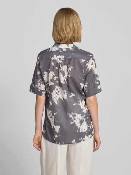 Vrouwenmodel draagt Relaxed Fit Kurzarmbluse aus reiner Baumwolle van Marc O'Polo in grijs met wit bloemenpatroon, Dames blouse met korte mouwen, Ganzkörperansicht Rückansicht.