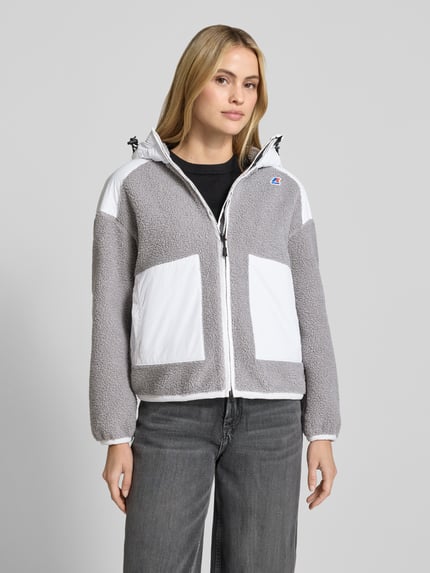 Frauenmodel trägt Teddyjacke mit Label-Detail und Zweiwege-Reißverschluss von K-WAY in Grau und Weiß, texturierte Optik, Regular Fit, Ganzkörperansicht von vorne. Rückenlänge 62 cm, Schulterbreite 58 cm, Brustweite 58 cm, Ärmellänge 52 cm.