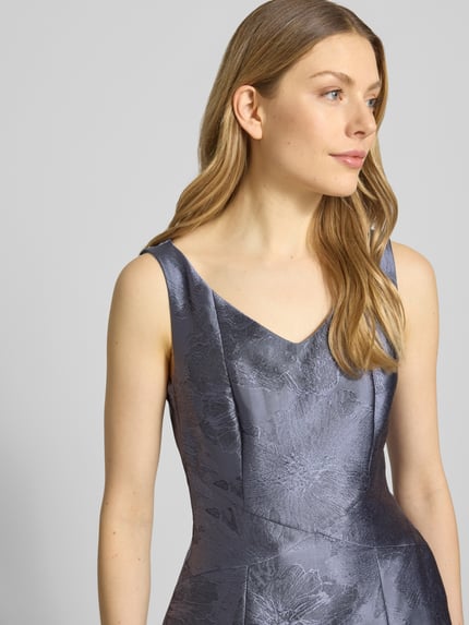 Frauenmodel trägt Regular Fit Abendkleid mit Florales-Allover-Muster von Swing in Grau, taillierte A-Linie, V-Ausschnitt, Ärmelloses-Design, strukturierte Textur, schimmernder Stoff, Nahaufnahme Oberkörper. Rückenlänge 134 cm, Brustweite 45 cm in Größe 36.