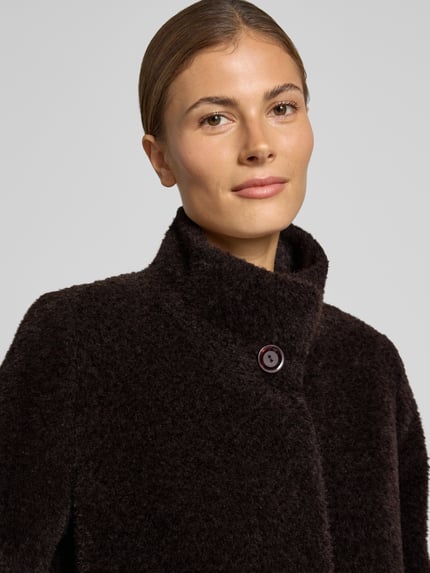Frauenmodel trägt Mantel aus Schurwolle-Alpaka-Mix mit Stehkragen von ICONS Cinzia Rocca in dunklem Braun, strukturierte Oberfläche, Knopfverschluss, Nahaufnahme Oberkörper.