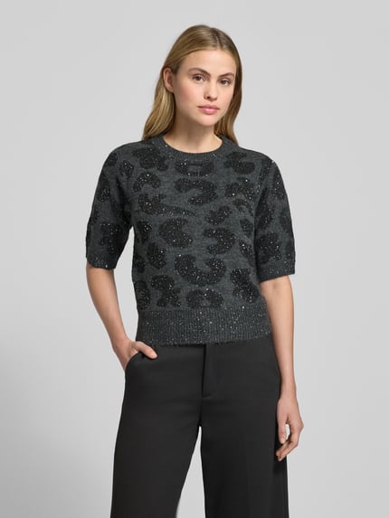 Kobiece model prezentuje Shaped Fit Strickpullover mit Woll-Anteil Modell 'ZUZU 2/4 O-NECK PULLOVER' od Vero Moda, szary melanż, połyskująca przędza, abstrakcyjny wzór, cekiny, 1/2 rękaw, widok całej sylwetki z przodu.