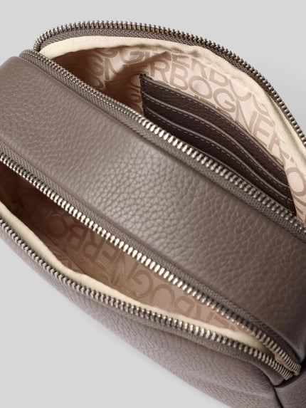 Produktfoto, graubraune Handtasche mit Schulterriemen Modell 'wallis avy' von BOGNER, Reißverschluss, strukturierte Leder-Optik, Detailaufnahme, Hauptfach und Kartenfach sichtbar, Label-Applikation, Innenfutter mit Markenprint, Maße: 23x14x7 cm, Riemenlänge 142 cm.