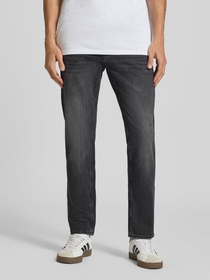 Männermodel trägt Regular Fit Straight Fit Jeans mit Label-Patch von JACK & JONES in Dark Wash Denim mit Used Look, Ganzkörperansicht von vorne.