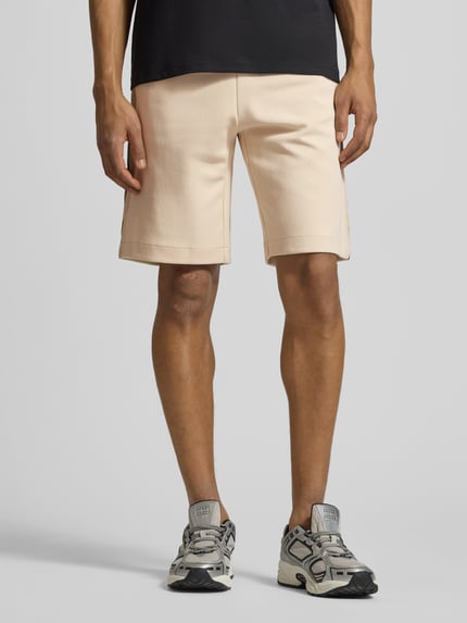 Männermodel trägt Shorts mit elastischem Bund von EA7 Emporio Armani, Baumwoll-Mix in Beige, Regular Fit, Nahaufnahme Oberschenkel, Vorderansicht.